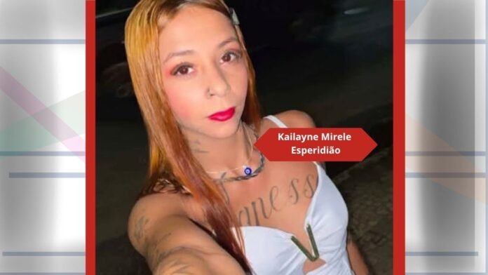 Selfie of a tattooed woman with long hair, red lipstick, and a white top taken at night outdoors.