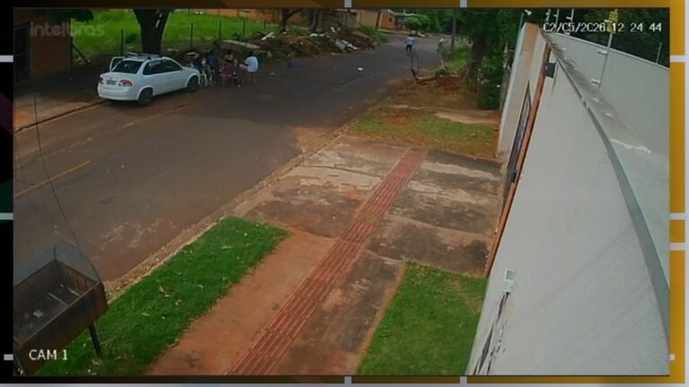 CCTV image from CAM 1: a white car parked on a residential street with a small group of people nearby and a sidewalk with red tactile paving along a wall on the right.