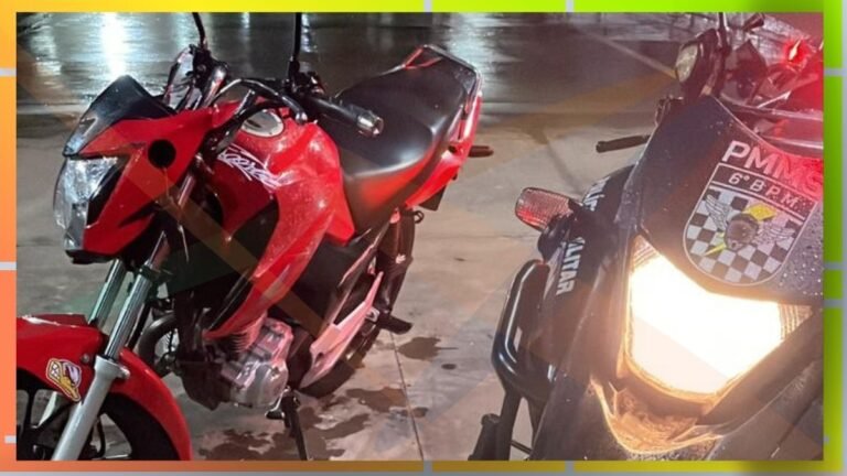Two red motorcycles parked on a wet street at night, one facing the camera with its headlight on and a police badge visible on the other bike's front shield.