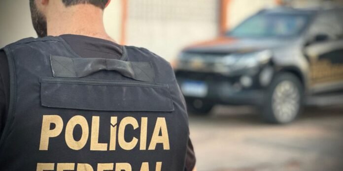 Back view of a police officer wearing a vest with POLICIA printed on it, a patrol SUV blurred in the background.