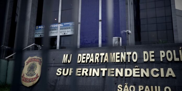 Close-up of a Brazilian Polícia Federal sign on a dark building with bars in the foreground and a shield emblem on the left.