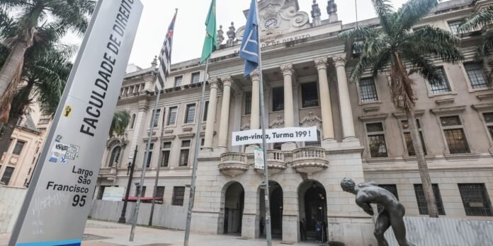 Grand law school facade with tall columns, flags, and a welcome banner reading 'Bem-vinda, Turma 199!'