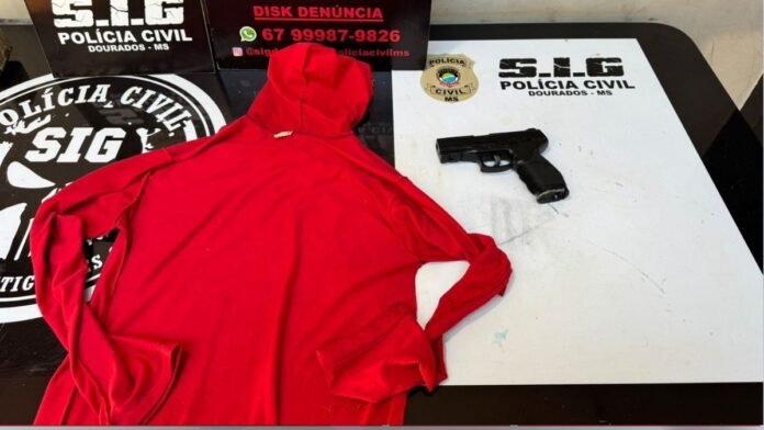 Red hooded sweatshirt laid on a table next to a black handgun, with Polícia Civil SIG branding visible in the background.