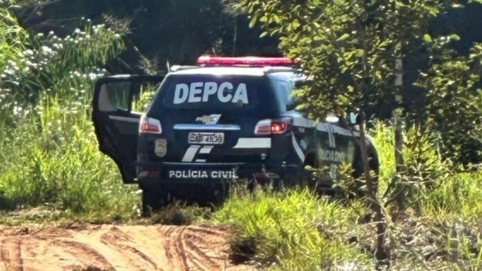 Rear view of a Polícia Civil SUV with 'DEPCA' markings parked on a dirt path in a grassy, rural area (back doors open).