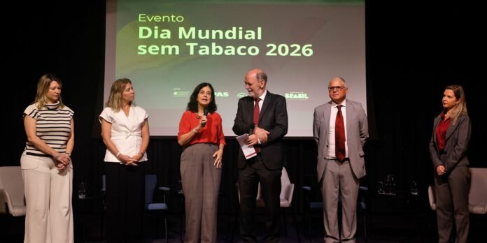 Six people stand on a stage in a panel setup, a screen behind them reads 'Dia Mundial sem Tabaco 2026'.