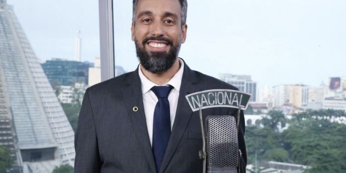 Smiling man in a dark suit at a microphone labeled Nacional, in a bright city studio background (informational image).