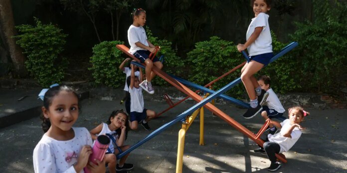 Group of children playing on a colorful seesaw in a park, smiling and having fun.
