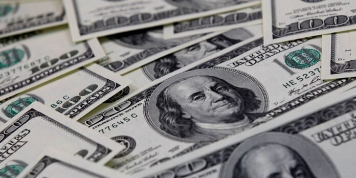 Close-up of scattered US $100 bills featuring Benjamin Franklin and green Treasury seals, stacked and overlapping backdrop of currency