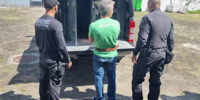 Three men with backs to the camera stand beside an open van; two uniformed officers flank a man in a green SEAPRO shirt on a paved area.