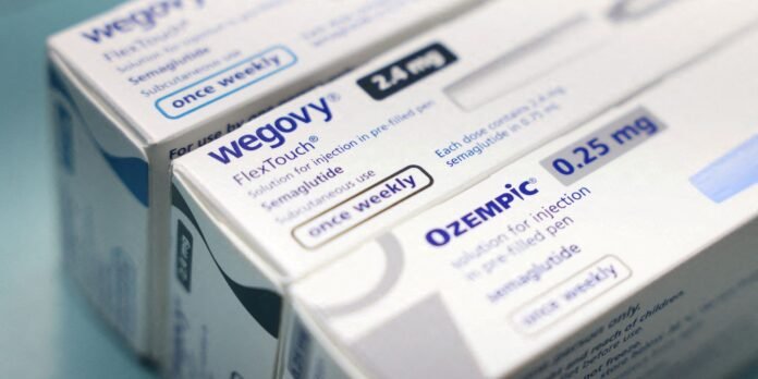 Close-up of white pharmaceutical boxes for Wegovy and Ozempic, showing dosage labels and blue text on a stack of cartons.