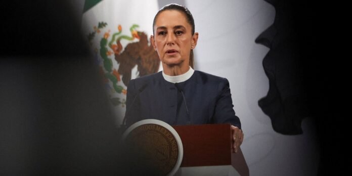 Female politician speaking at a podium with the Mexican flag in the background, seal visible on the lectern.