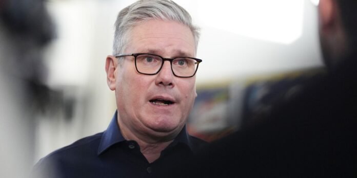 Man with gray hair and glasses speaks, facing interviewer in what looks like a studio or office setting