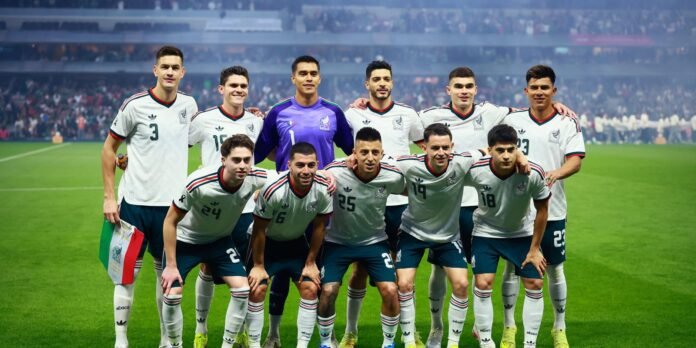 Mexican national soccer team posing for a group photo on the field before a match, goalkeeper in purple at center back edge of the group