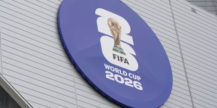 Purple circular sign on a gray striped wall: FIFA World Cup 2026 logo and trophy.