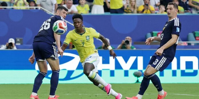 Brazilian footballer in yellow kit (#7) dribbles toward the ball as two opponents in navy blue defend nearby on the pitch.
