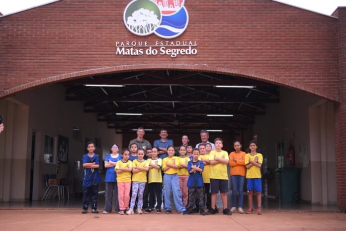 Group of children and adults posing under the brick entrance of Parque Estadual Matas do Segredo.