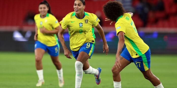 Brazil women's soccer players in yellow jerseys celebrate or move on the field during a match, central player wearing number 9 on blue shorts