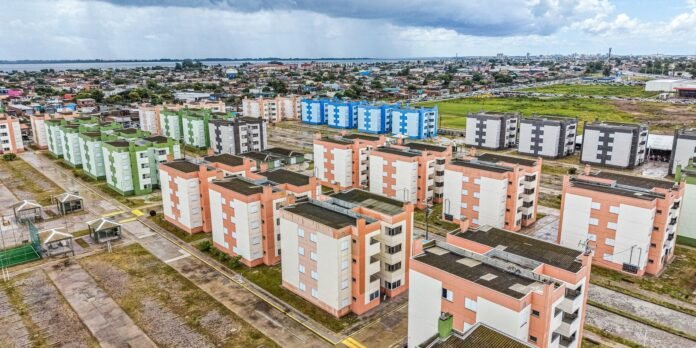 Aerial view of a colorful housing estate with pink, green, blue, and gray apartment blocks arranged in a grid.