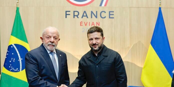 Two men shake hands in front of a France Évian backdrop, flanked by the Brazilian and Ukrainian flags on either side.
