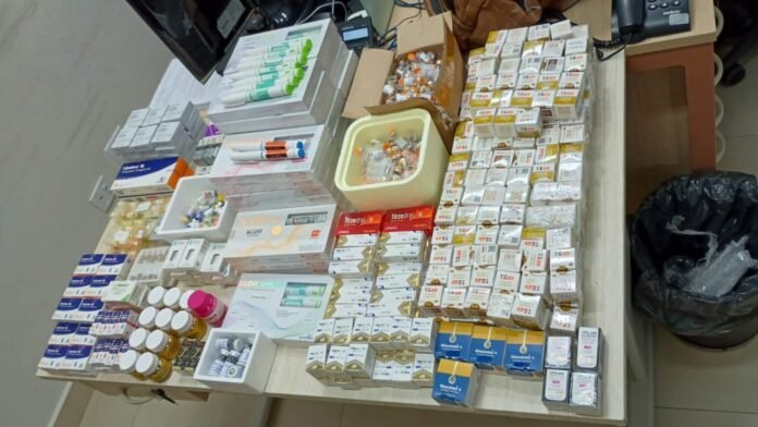 Top-down view of a desk filled with medicine boxes, vials, and syringes arranged in neat rows.