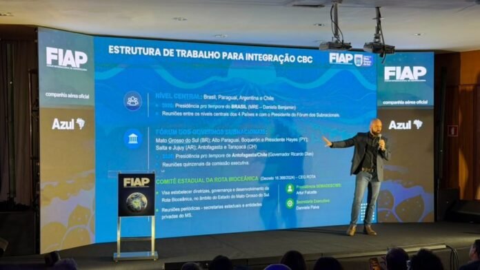 Speaker presenting on a stage beside a large blue slide titled 'ESTRUTURA DE TRABALHO PARA INTEGRAÇÃO CBC' at a FIAP event.