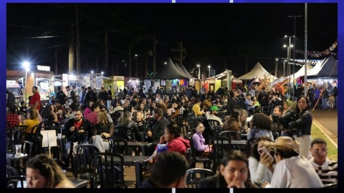 Night market at night with many people seated at tables, food stalls in the background and string lights overhead.