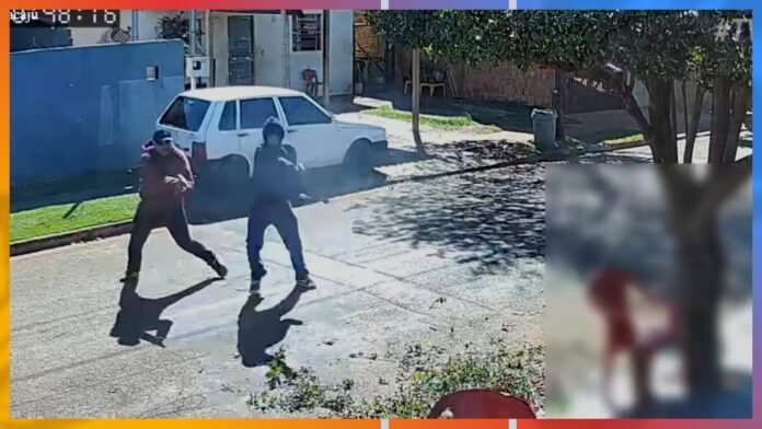 Two men armed with guns walk across a sunlit residential street beside a parked white car, with a second blurred figure visible in an inset on the right.