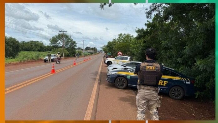 PRF officer in tactical vest overlooking a rural highway blocked by orange traffic cones and parked patrol cars.