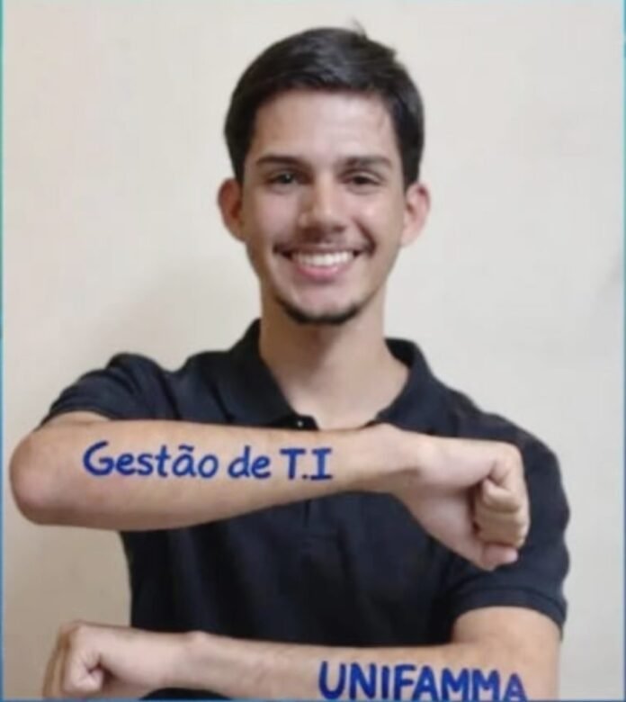 Smiling young man in a black shirt shows blue tattoo text on both forearms: 'Gestão de T.I' on one arm and 'UNIFAMMA' on the other.