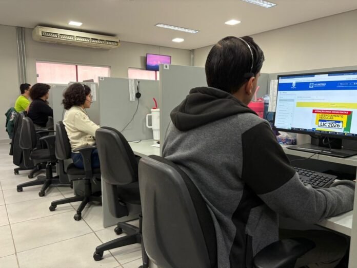 People seated at cubicle desks in a service center, using computers with headsets for assistance.