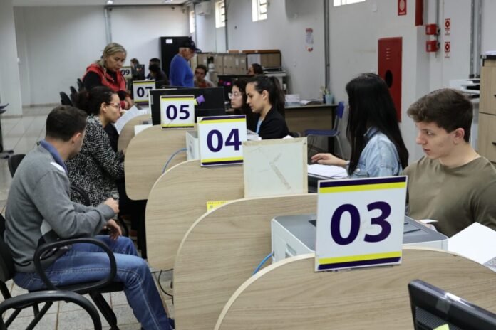 People seated at numbered service desks (03, 04, 05) in a busy office, helping customers with forms and documents.