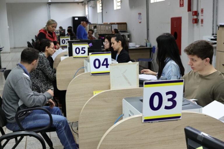 People seated at numbered service desks (03, 04, 05) in a busy office, helping customers with forms and documents.