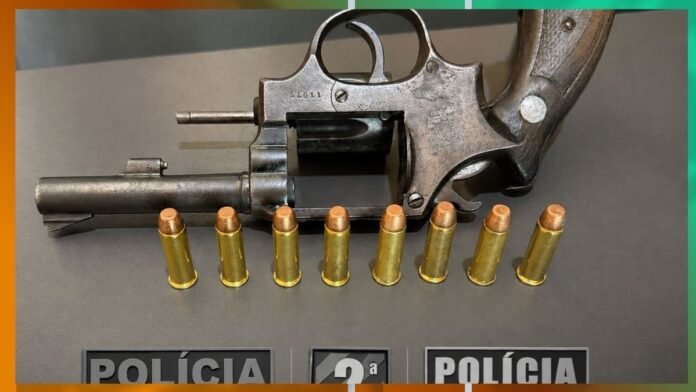 Antique revolver with eight cartridges lined up on a table beside police signs.