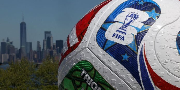 Close-up of a decorated FIFA World Cup football with a city skyline in the blurred background.