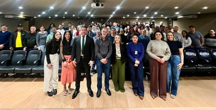 Diverse group posing for a photo in a lecture hall; front row standing, audience seated behind.