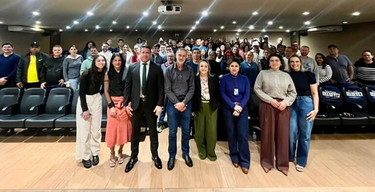 Diverse group posing for a photo in a lecture hall; front row standing, audience seated behind.