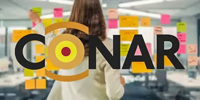 Brand name CONAR over a blurred office wall with colorful sticky notes and a person in the background.