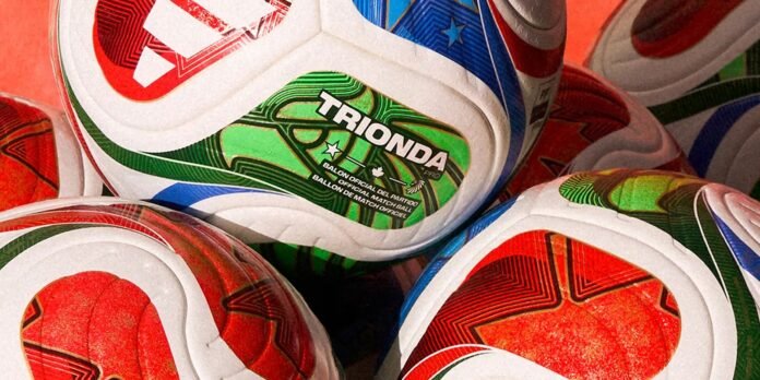 Close-up of stacked colorful sports balls with a green 'TRIONDA' branded ball in focus.