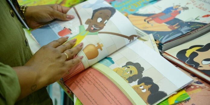 Close-up of hands turning pages in a colorful children's picture book as cartoons appear on the spread.