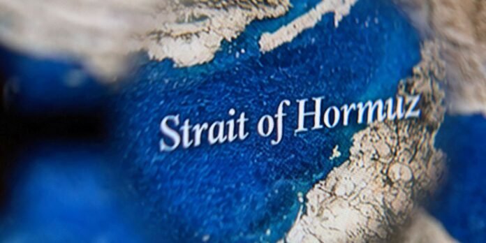 Close-up of a world map highlighting the Strait of Hormuz with blue water and beige landmasses.