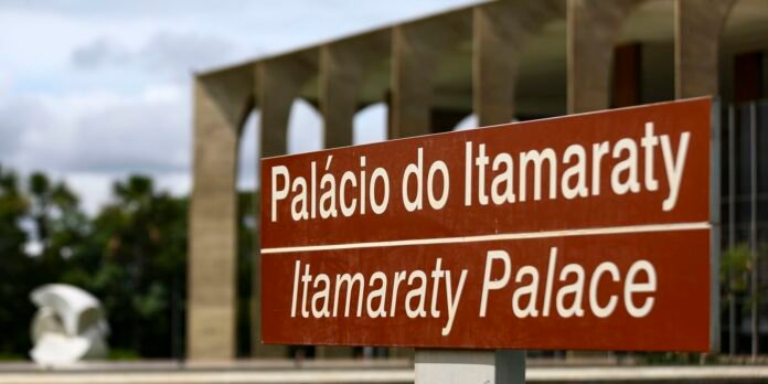 Sign reading 'Palácio do Itamaraty' and 'Itamaraty Palace' in white text on a brown background, with a blurred architectural facade behind it.
