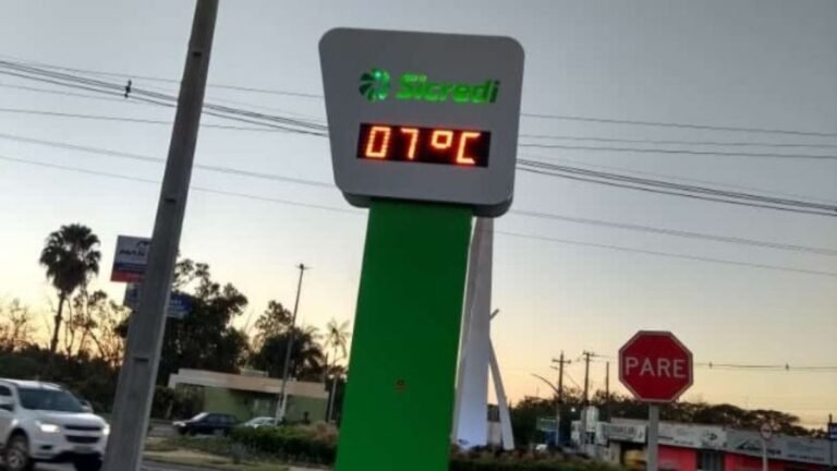 Gas station sign with digital temperature display reading 01°C, green branding, and a Pare stop sign in the background.