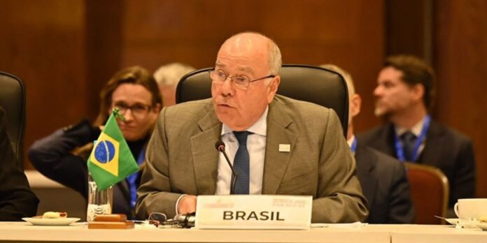 Brazilian delegate speaking into a microphone at a formal meeting with a Brazil flag and 'BRASIL' nameplate in view.