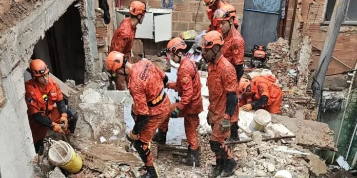 Rescue workers in orange gear and helmets navigating a rubble-filled site, inspecting debris and preparing tools for extraction.