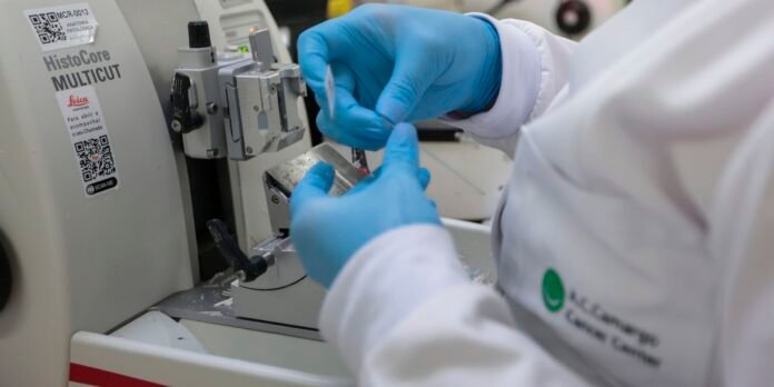 Lab technician wearing blue gloves adjusts a HistCore MULTICUT tissue slicer in a lab setting.