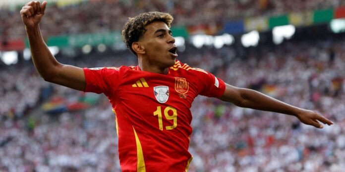 Soccer player in red jersey with number 19 celebrates with arms outstretched in a packed stadium.