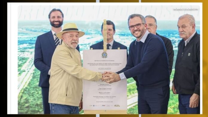 Grupo de homens em traje formal e casual, apertando as mãos diante de um grande certificado em uma cerimônia.