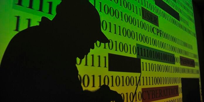 Hacker silhouette in a hoodie against a green background filled with binary code and security terms like USER, PASSWORD, and CYBER ATTACK.