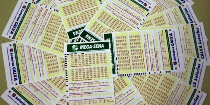Pile of Brazilian lottery tickets scattered on a surface, center features a Mega-Sena ticket in green and white.