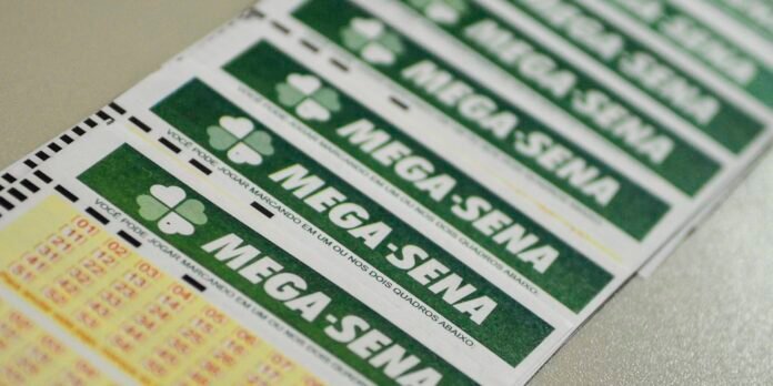 Close-up of Brazilian Mega-Sena lottery tickets with green panels and a four-leaf clover logo, showing the game name 'MEGA-SENA' and numbers area clearly visible.